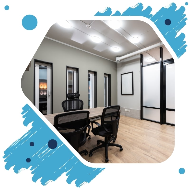 A brightly lit conference room with a wood table and black chairs set for a meeting.