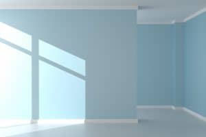 Empty room with blue walls and a window shadow, prepared for interior painting