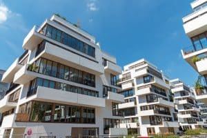 A row of modern apartment buildings with white balconies against a clear blue sky. This image showcases a neutral colour palette, a popular choice for strata exteriors due to its clean and timeless aesthetic.