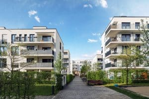 A row of modern white apartment buildings with balconies in a suburban residential area. The buildings have a neutral colour palette, which is a popular choice for strata exteriors because it is timeless, versatile, and easy to maintain.