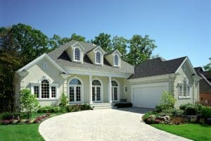 Image of a large white house with a green exterior paint colour and a driveway leading up to it.