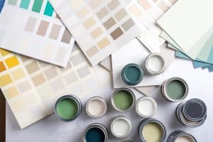 Close-up of several unopened cans of green exterior paint colour on a table.