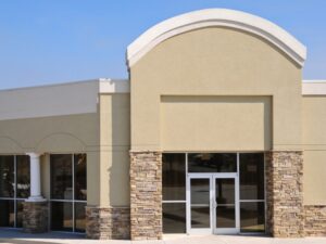 A commercial building with beige walls and stone accents, illustrating wall painting techniques for exterior durability.