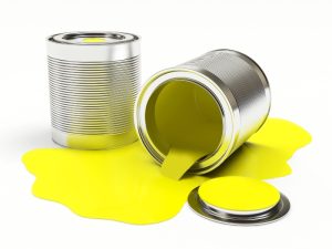 Spilled yellow paint from overturned cans, illustrating common mishaps and tips on how to dispose of paint properly.