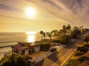 Sunset over coastal homes with palm trees, highlighting the best house painting for seaside properties.