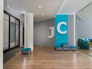 Modern office lounge with JC logo and blue accent wall showcasing creative office painting ideas.