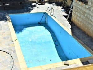 Empty swimming pool with old paint; preparing to remove pool paint for a new coat.