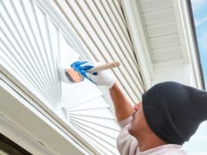 A professional painter in a beanie painting an exterior decorative panel to prevent bubbling paint caused by poor adhesion.