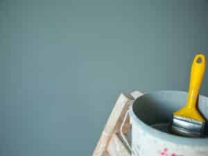 A tin of paint and a brush, reflecting on house painting costs in Australia.