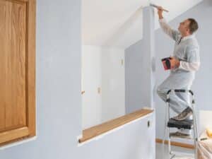 Quality painters using ladder and precision tools to paint interior walls with care and professional finish.