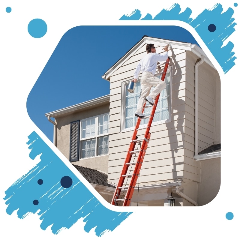 Professional house painter in Sydney on ladder painting second-storey exterior wall of modern home under clear blue sky.
