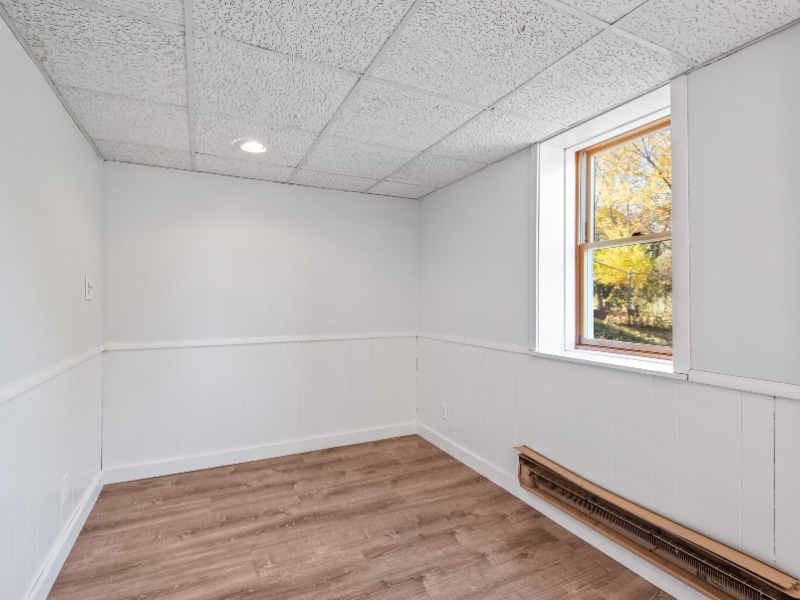 Empty room before wall painting with white walls and wooden flooring.